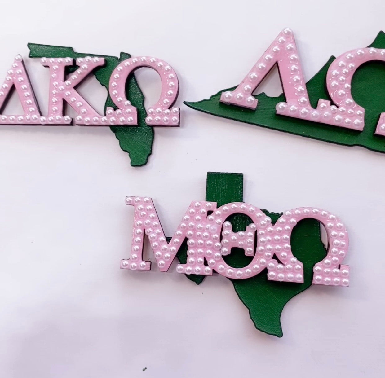Set of pink and green Alpha Kappa Alpha sorority brooches with state, chapter name, and pearls.